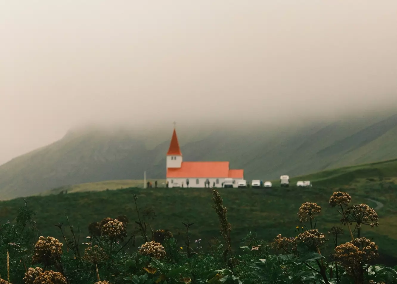 Enchanting Red-Roofed Church Amidst Misty Icelandic Hills