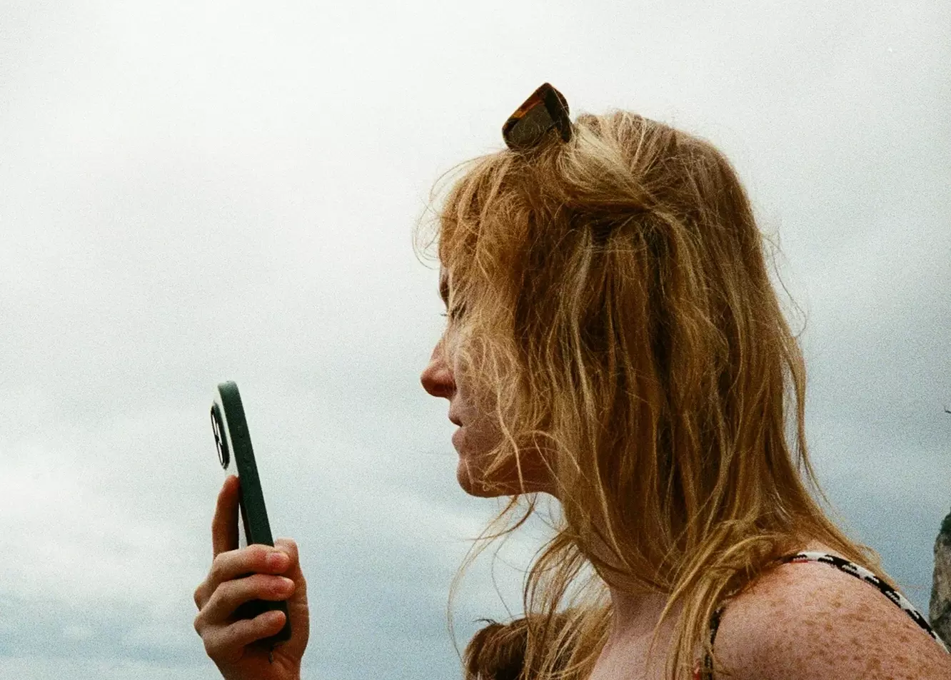 Captivating Coastal Moment: Woman Engaged with Phone by the Ocean