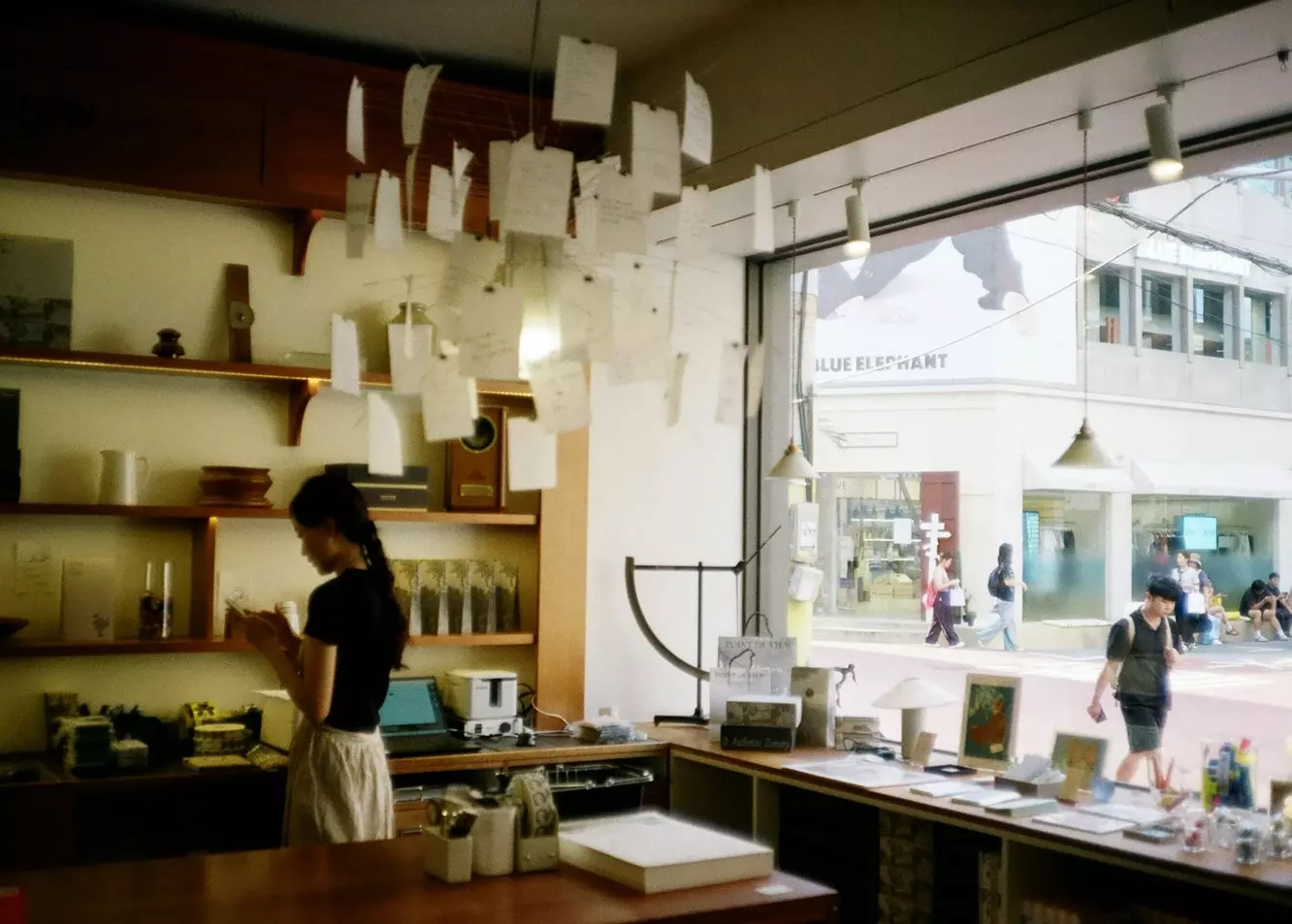 Charming Bookstore View: Woman Browsing with Urban Streetscape