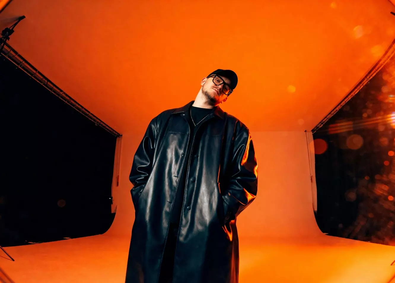 Vibrant Orange Studio: Stylish Man in Long Black Coat