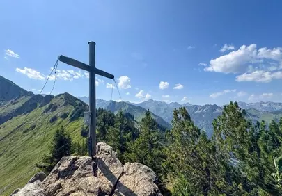 Breathtaking Alpine Summit: Majestic Cross Overlooking Verdant Peaks
