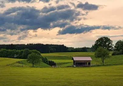 Serene Sunset: Barn Amidst Golden Fields & Dramatic Skies