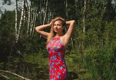 Stunning Blonde in Red Floral Dress Amidst Lush Forest