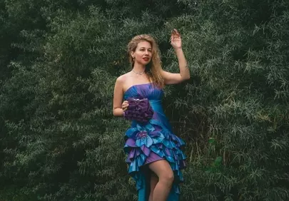 Enchanting Blonde in Purple Evening Gown Amidst Lush Nature
