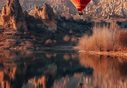 Breathtaking Red Hot Air Balloon Soaring Over Mountainous Reflections