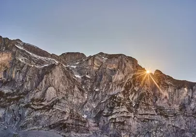Breathtaking Alpine Sunrise: Golden Sunburst over Craggy Peaks