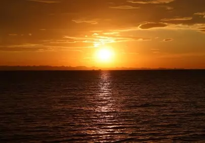 Breathtaking Golden Hour: Serene Ocean Sunset Over Distant Mountains