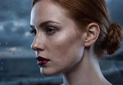 Enchanting Freckled Woman Gazing Through Rainy Window