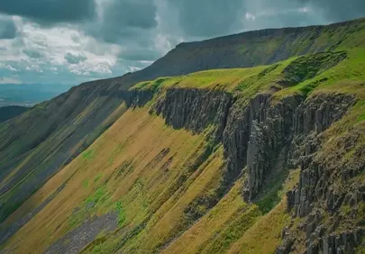 Dramatic Alpine Majesty: Lush Cliffs Under Dynamic Skies
