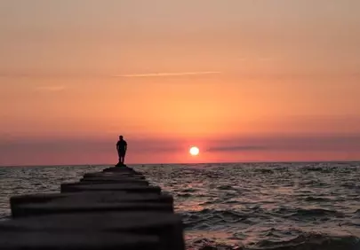 Breathtaking Sunset Silhouette: Lone Figure on a Pier