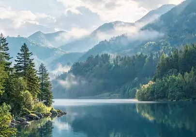 Serene Mountain Lake Reflects Misty Green Peaks
