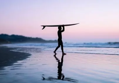 Serene Sunset Surfer: Silhouette on a Reflective Beach