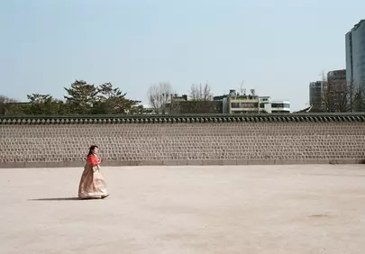 Graceful Hanbok: Woman Strolling by Ancient Stone Wall