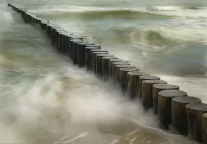 Serene Coastline: Wooden Pillars Battling Foamy Waves