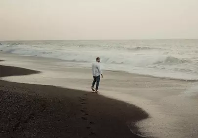 Serene Solitude: Man Walking on a Quiet Sunset Beach