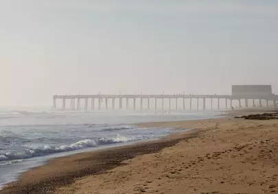 Misty Morning Ocean: Tranquil Pier and Waves at Dawn