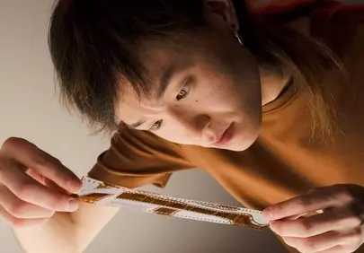 Captivating Gaze: Young Man Scrutinizing Film Negatives