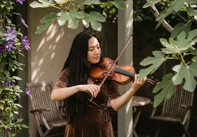 Serene Melodies: Woman Plays Violin Amidst Lush Greenery