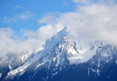 Majestic Snow-Capped Peak Amidst Whispering Clouds