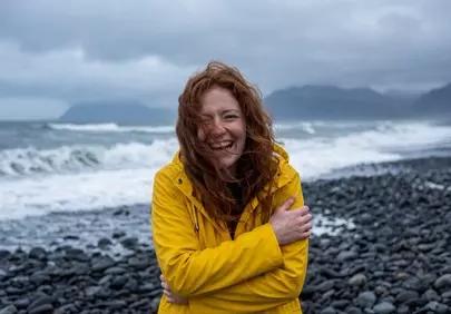 Joyful Redhead Braves Stormy Beach in Vibrant Yellow Raincoat