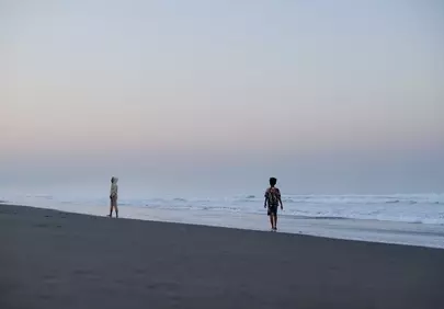 Serene Dawn: Children's Play on Volcanic Sand Beach