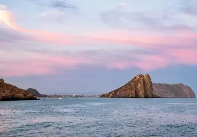 Breathtaking Coastal Sunset: Serene Sea and Dramatic Rock Formations
