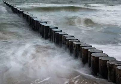 Dramatic Coastal Erosion: Ocean Waves and Weathered Wooden Pilings