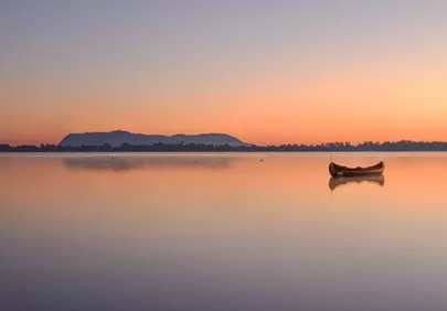 Serene Quebec Sunrise: Lonely Canoe on Tranquil Lake