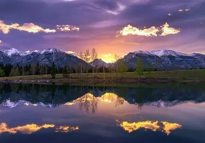 Breathtaking Sunset Over Majestic Mountains Reflected in Calm Waters