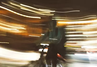 Vibrant Night Blur: Cyclist's Dynamic Journey Through City Lights