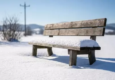 Serene Snow-Covered Bench in Winter Sunlight