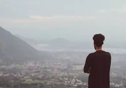 Breathtaking Mountain Vista: Man Reflects in Solitude
