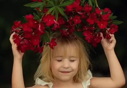 Charming Child Embracing Nature's Red Oleander Blooms