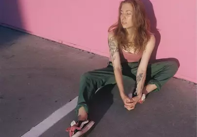 Vibrant Urban Chill: Tattooed Woman by a Pink Wall