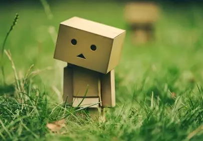 Charming Cardboard Robot Embraces Nature in Lush Green Grass