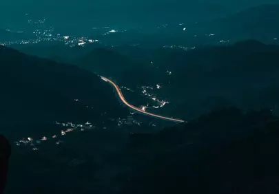 Enchanting Night Landscape: Serpentine Highway Illuminates Mountainous Terrain