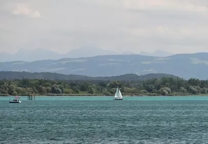 Serene Lake Constance: Sailboat Gliding Amidst Majestic Mountains