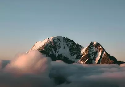 Majestic Snow-Capped Peaks Above Clouds at Sunset
