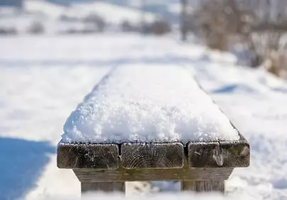 Serene Winter Day: Snow-Covered Bench in Idyllic Countryside