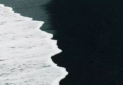Dramatic Contrast: White Waves on Black Sand Beach