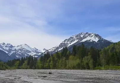 Majestic Alpine Panorama: Snow-Capped Peaks and Serene River Valley