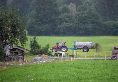 Rustic Charm: Tractor Spreading Manure in Lush Mountain Pastures