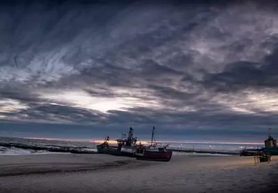 Dramatic Coastal Sunset: Fishing Boats on the Shore
