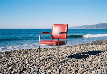 Serene Solitude: Red Chair on a Tranquil Pebble Beach