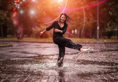 Joyful Woman Splashing in Puddles at Sunset