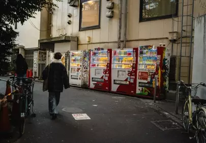Vibrant Alley: Person Walks Past Illuminated Vending Machines