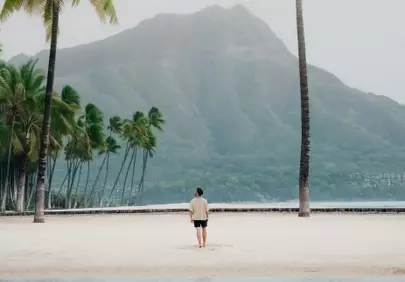 Serene Tropical Escape: Man on a Secluded Beach with Majestic Mountains