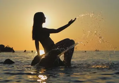 Golden Sunset Serenity: Girl Splashing Water at Beach