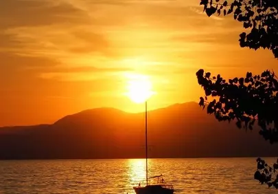Breathtaking Sunset over Tranquil Lake with Silhouetted Boats