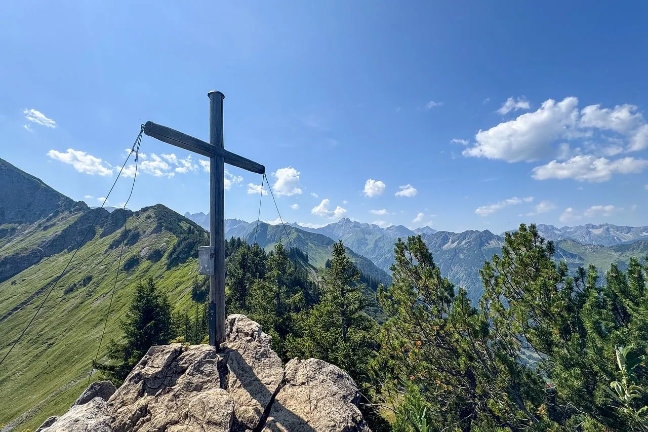 Breathtaking Alpine Summit: Majestic Cross Overlooking Verdant Peaks